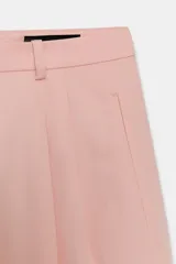 Pantalón de tiro medio con corte wide leg, confeccionado en algodón. Presenta cintura con trabillas, bolsillos laterales ocultos y detalle de pliegues en el delantero. Cierre frontal con cremallera, botón y ganchos metálicos.