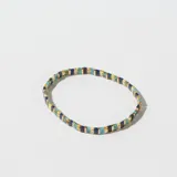 Pulsera elástica con cuentas rectangulares de colores azul, celeste, marrón y blanco, separadas por pequeñas piezas metálicas doradas.