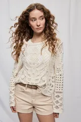 Sweater corto color crudo de manga larga, confeccionado en crochet calado con diseño artesanal y silueta amplia.