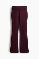 Pantalón de tiro alto confeccionado en punto roma, con diseño ajustado en la parte superior y piernas acampanadas. Presenta bolsillos insertados decorativos en la parte frontal.