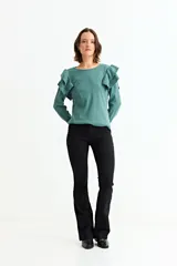 Remera de manga larga en color crudo, confeccionada en tejido acanalado, con detalle de volados en los hombros y cuello redondo.