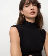 Vestido midi de punto color negro, con cuello alto, hombreras y tajo lateral. Diseño ajustado al cuerpo.