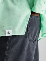 Camisa verde menta de rayón arrugado, corte regular, cuello en punta, manga larga con puños abotonados y espalda dividida con detalle anudado.