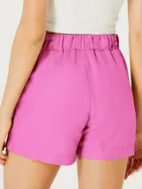 Short femenino color fucsia, de tiro alto con cintura elástica fruncida y lazo ajustable a tono. Presenta pliegues frontales y bolsillos laterales.