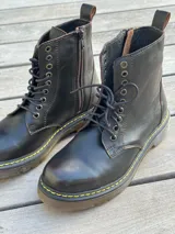 Bota corta de cuero color chocolate, con cordones amarillos y cierre lateral.