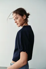 Top de punto color azul marino, con cuello redondo y mangas cortas abullonadas con acabados elásticos fruncidos.