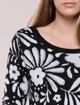 Buzo tejido de punto fino negro con diseño de flores blancas a contraste, escote redondo y mangas de largo al codo.
