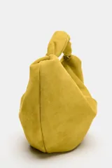 Bolso de mano de piel color verde mostaza, con cuerpo fruncido, asa de mano con detalle retorcido, cadena metálica opcional para función bandolera y cierre mediante cremallera.