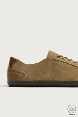 Zapatilla deportiva barefoot de hombre, confeccionada en piel con acabado serraje de color marrón, puntera redondeada, suela fina de goma oscura y detalles en cuero liso en el talón.