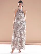 Vestido largo blanco con estampado floral en tonos marrones. Tiene cuello halter y corte holgado.