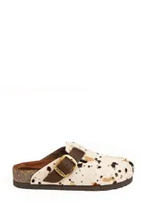 Zueco de cuero con estampado animal print de vaca en tonos beige, marrón y negro. Cuenta con una tira ajustable de cuero marrón con hebilla metálica dorada y base de corcho.