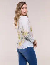 Blusa de silueta holgada y corte recto con caída fluida, escote redondo y mangas largas con puños anchos estructurados, con estampado floral en tonos pasteles sobre fondo blanco.