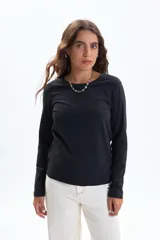 Remera de manga larga en color negro, confeccionada en tejido con elastano para un ajuste cómodo y entallado. Presenta cuello redondo clásico y diseño minimalista.