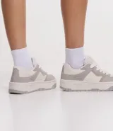 Championes de caña corta marca Satinato, confeccionados en material sintético tipo cuero (PU). Presentan un diseño de paneles en tonos beige y tostado, con suela de plataforma tipo caja y cierre mediante cordones.