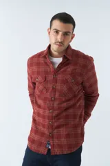 Sobrecamisa de algodón a cuadros color ladrillo, con interior de corderito, cierre con botones, bolsillos tipo cartera y logo en goma. El modelo usa talle M.