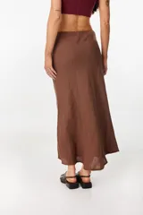Falda larga color beige de corte sirena confeccionada en lino italiano, con pretina interior elástica y diseño fluido.