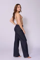 Jean de corte wide leg y tiro bajo, color azul oscuro, con costuras laterales desplazadas hacia el frente y cierre frontal con botón.