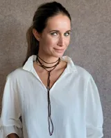 Collar estilo corbatín confeccionado en tiento de cuero color suela, con detalle de cuentas metálicas plateadas distribuidas a lo largo de las tiras.