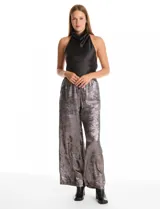 Pantalón wide leg de tela laminada metalizada color blanco, con pretina elástica y lazo de ajuste en la cintura. Cuenta con bolsillos laterales.