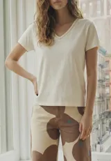 Remera de manga corta con escote en V, confeccionada en una mezcla de viscosa y elastano que le otorga suavidad y una caída fluida. Presenta un diseño liso con un calce entallado al cuerpo.