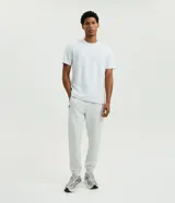 Pantalón jogger deportivo de color gris claro, con cintura elástica con cordón de ajuste, bolsillos con cremallera y bajos elásticos acanalados. Marca Get Over.