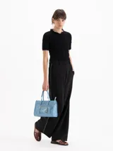 Pantalón sastre color negro de corte recto y tiro alto, confeccionado en mezcla de viscosa y elastano. Presenta bolsillos laterales, presillas para cinto y un delicado vivo decorativo a lo largo de los laterales.