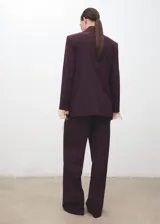 Pantalón de vestir bordó de tiro medio, con diseño wide leg, pinzas en la parte delantera, bolsillos laterales y cierre frontal con botón, gancho y cremallera.