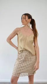 Pollera corta de encaje con diseño de flores caladas y destellos de lurex, con forro interior al tono.