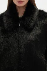 Campera de piel sintética color negro, con cuello, manga larga y cierre frontal. Presenta un diseño de corte holgado y textura suave.