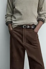 Pantalón de corte straight fit confeccionado en ante de color marrón, con diseño de cinco bolsillos y cierre frontal con cremallera y botón.