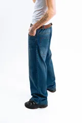 Pantalón de jean azul oscuro con efecto desgastado, corte mega baggy de tiro alto y pierna ancha. Presenta cinco bolsillos y botones personalizados.
