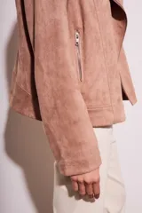Campera tipo biker de gamuza sintética color rosa viejo, con cierre frontal cruzado, solapas con broches metálicos y bolsillos laterales con cierre.