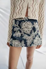 Falda pantalón corta de color azul marino con diseño bordado de flores en hilo crudo, forro interior y cierre lateral con cremallera oculta.
