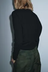 Jersey de punto color marrón oscuro, con cuello redondo, manga larga y hombreras con pliegues.