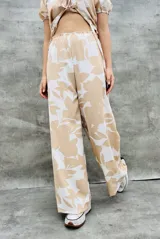 Pantalón palazzo de tiro alto con estampado de flores grandes en tonos beige y blanco.