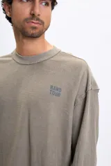 Remera de manga corta color verde oliva, confeccionada en tejido french terry, con estampado en la espalda que simula un cartel de gira de banda con fechas y lugares.