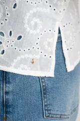 Blusa blanca de manga larga con cuello camisero y bordado tipo broderie anglaise con diseño floral calado.