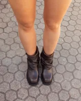 Botas cortas de cuero color marrón con efecto desgastado, diseño de caña holgada con pliegues, hebilla lateral metálica y suela track dentada.