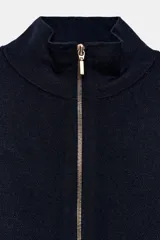 Chaqueta de punto color azul marino, de cuello alto y manga larga, con cierre frontal de cremallera metálica y detalle de abertura en el bajo delantero.