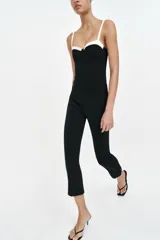 Body negro con diseño estructurado, escote corazón con aros y detalles en color blanco contrastante en la parte superior y en los tirantes finos ajustables.