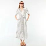 Vestido camisero largo de manga corta en mezcla de algodón y lino, con diseño de rayas verticales en tonos marrón, azul y blanco. Cuenta con cuello en V, cierre frontal abotonado y un lazo ajustable para atar en la cintura.