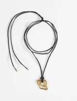 Collar de cordón largo negro con dije de forma irregular en tono dorado, fabricado en acero quirúrgico.