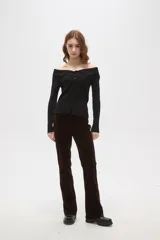 Top de punto acanalado color negro, con escote estilo strapless y cierre frontal con botones. Presenta mangas largas y un ajuste al cuerpo.