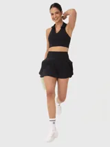 Falda deportiva negra con calza interior, de corte acampanado con vuelos en la parte trasera. Cuenta con un pequeño bolsillo con cierre en la pretina y otro bolsillo en el interior de la calza.