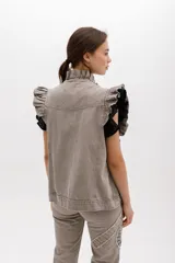 Chaleco de denim azul con estampado paisley, sin mangas, con volados en hombros y cuello, cierre frontal con botones metálicos y bolsillos laterales.