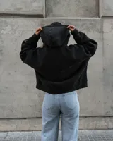 Canguro negro con capucha y cierre frontal, con texto bordado en el pecho y bolsillos laterales.