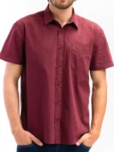 Camisa de manga corta color celeste claro, confeccionada en algodón, con cuello clásico y un bolsillo de parche en el lado izquierdo del pecho.