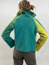Pantalón tipo babucha confeccionado en lana de oveja, color visón. Presenta un diseño de tiro alto con textura vertical plisada a lo largo de las piernas, cintura con cierre de doble broche y puños elásticos en los tobillos.