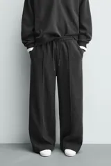 Pantalón de corte wide fit en tejido con acabado cepillado, color gris oscuro. Presenta cintura elástica con cordón ajustable, bolsillos delanteros y bolsillos traseros de plastrón.
