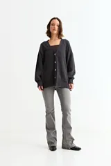 Cardigan de punto con cuello en V, cierre frontal con botones y bolsillos laterales. Presenta un diseño holgado y mangas largas con puños acanalados.